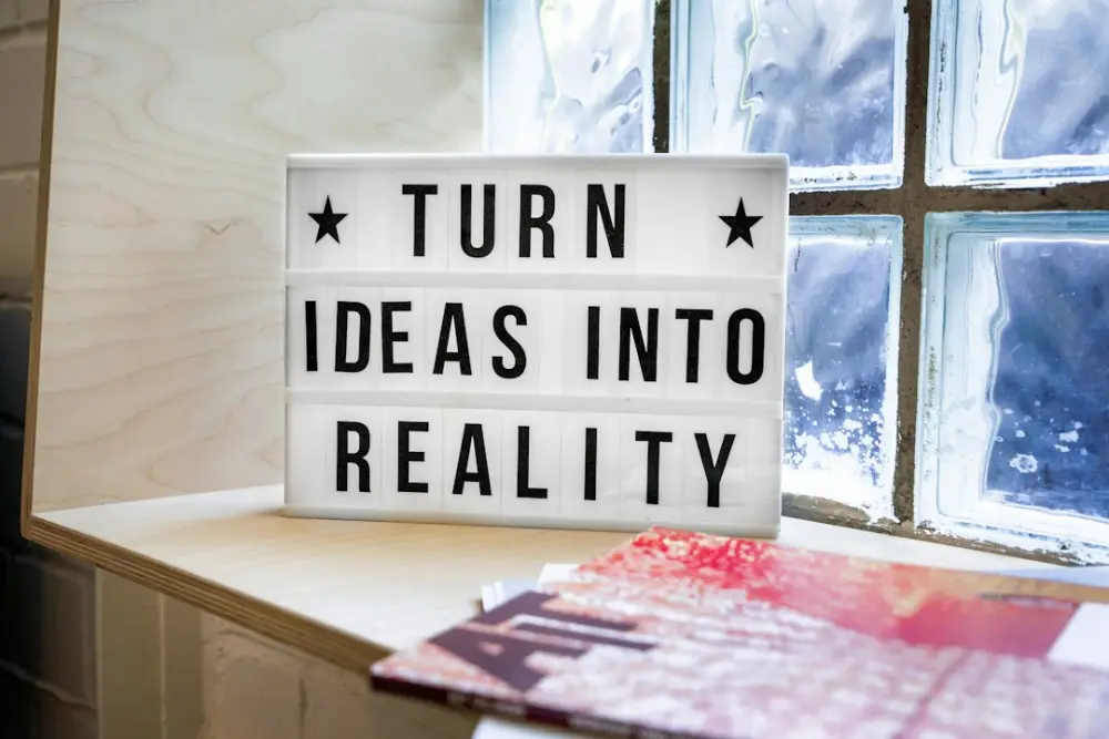 A light box sign reading "TURN IDEAS INTO REALITY" on a wooden shelf
